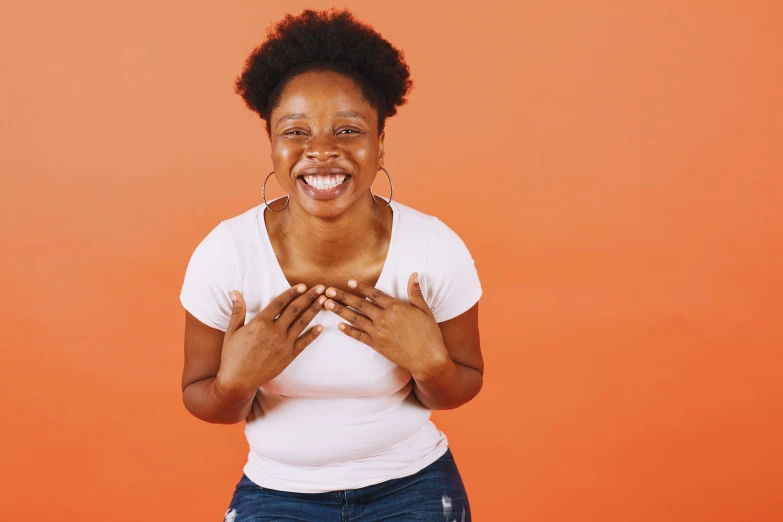 a woman making a heart sign with her hands, by Carey Morris, brown skin man with a giant grin, white and orange breastplate, portrait featured on unsplash, on simple background