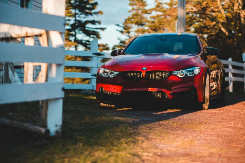 a red car parked in front of a white fence, pexels contest winner, bmw, golden hour 4k, fan favorite, wide views