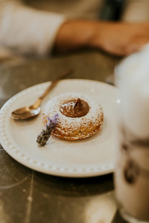 a white plate topped with a pastry next to a cup of coffee, inspired by Richmond Barthé, unsplash, romanticism, lavender, blender donut, 2 5 6 x 2 5 6 pixels, gourmet michelin restaurant