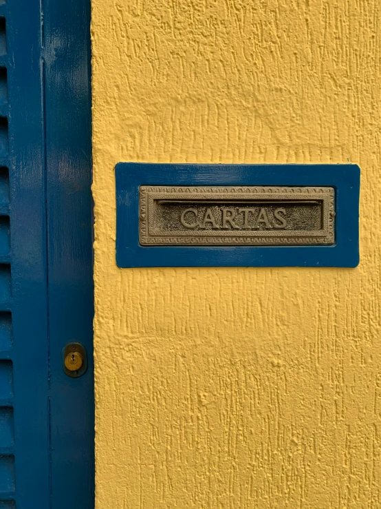a sign that is on the side of a building, inspired by Carlos Berlanga, pexels contest winner, letterbox, yellow walls, azores, prussian blue and raw sienna