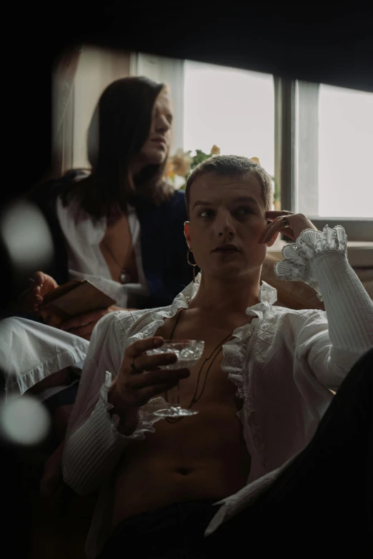 a group of people sitting on top of a bed, an album cover, inspired by Nan Goldin, trending on unsplash, renaissance, delicate androgynous prince, holding a glass of wine, white russian clothes, tom holland