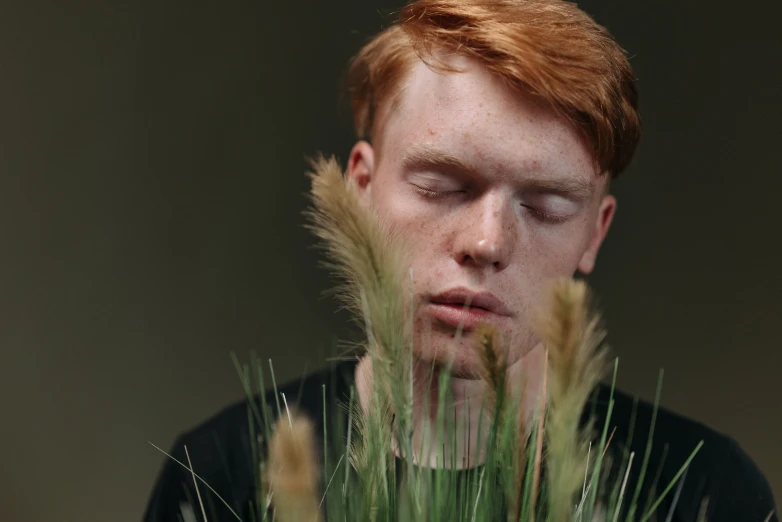a close up of a person in a field of grass, trending on pexels, hyperrealism, red haired teen boy, covered in plants, thoughtful ), well-groomed model
