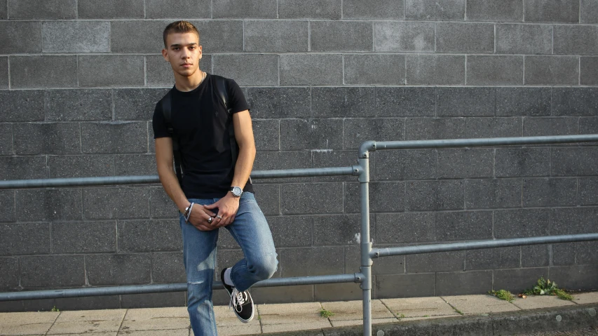 a young man standing in front of a brick wall, inspired by Jean Malouel, pexels contest winner, les nabis, wearing a dark shirt and jeans, jamel shabbaz, without text, wide full body