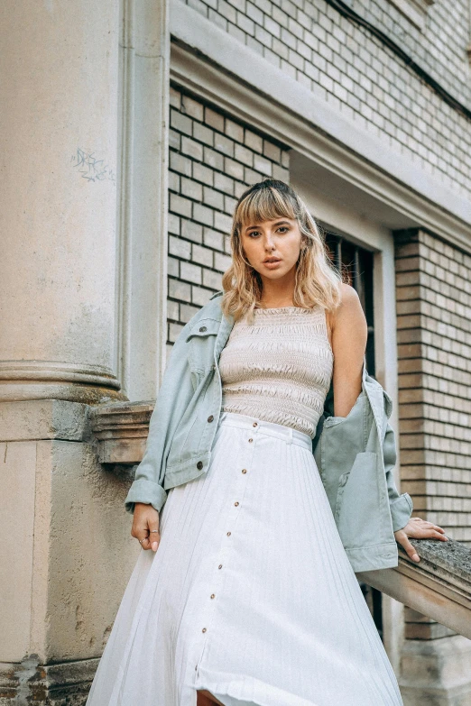 a woman standing in front of a building wearing a white dress and jacket, inspired by Elsa Bleda, trending on pexels, wearing a tanktop and skirt, sydney sweeney, promotional image, wearing military outfit