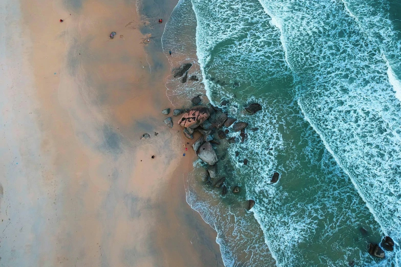 a large body of water next to a sandy beach, pexels contest winner, renaissance, air shot, rocks falling, sri lanka, leaking