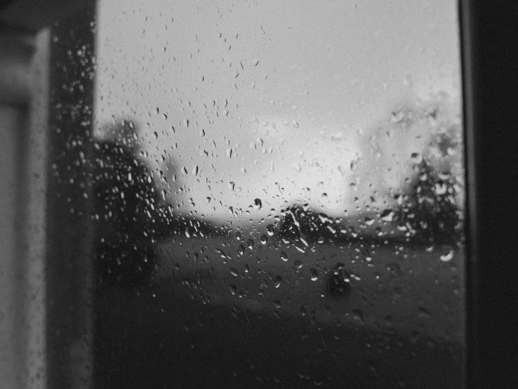 a black and white photo of a rain covered window, by Emma Andijewska, uploaded, driving rain, midday photograph, looking outside