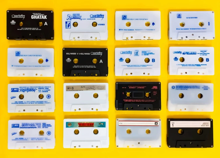 a group of cassettes sitting on top of a yellow surface, grid of styles, white + blue + gold + black, lined up horizontally, most popular