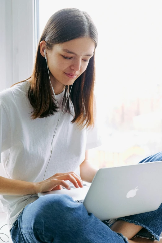 a woman sitting on a window sill using a laptop, trending on unsplash, wearing a white button up shirt, student, girl wearing headphones, official screenshot