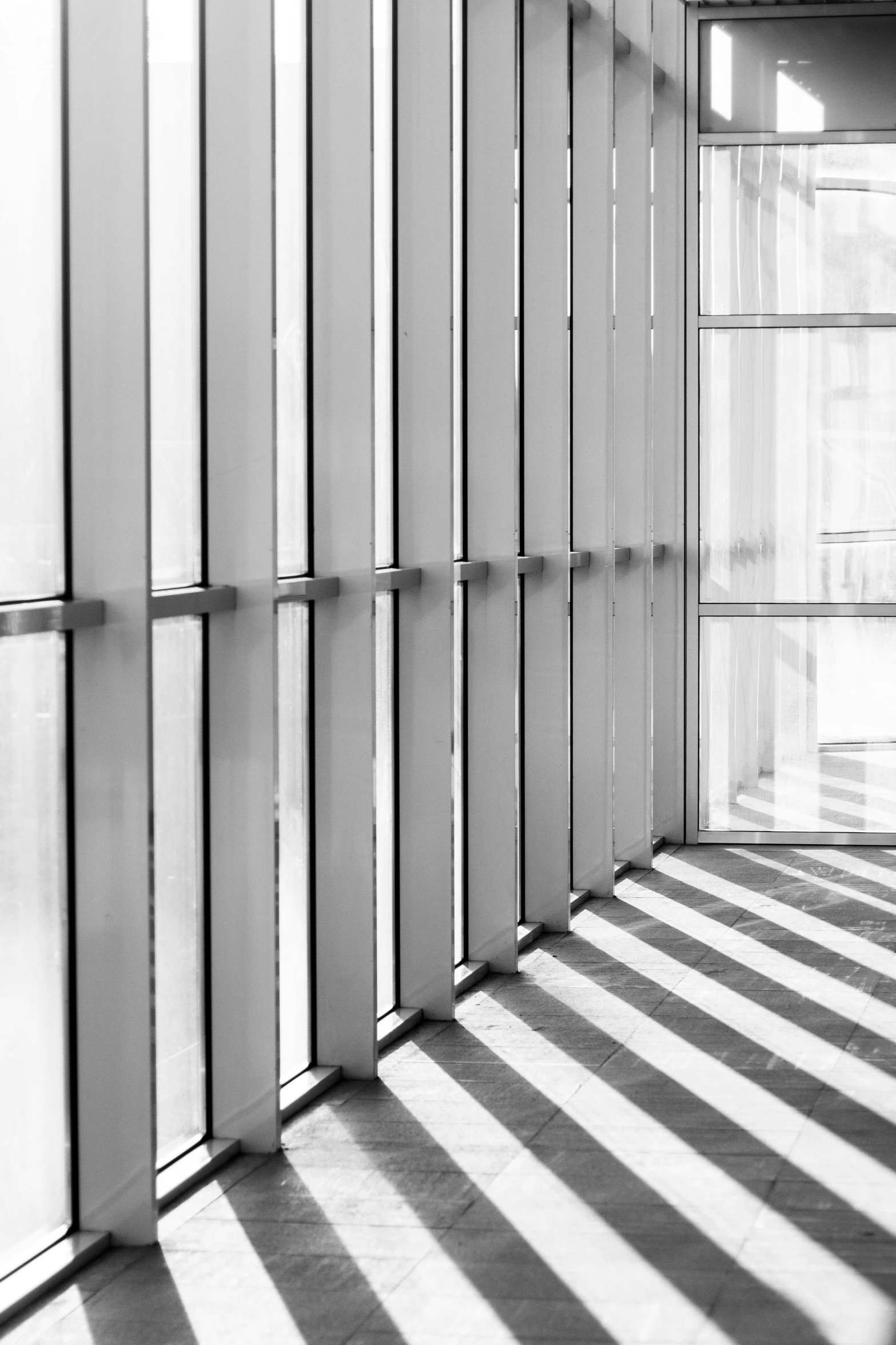 a black and white photo of a hallway, inspired by Donald Judd, flickr, light and space, morning sun - rays, metal cladding wall, glass wall, striped