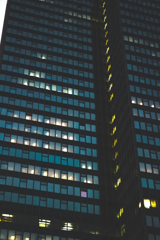 a tall building with many windows lit up at night, unsplash, brutalism, 1960s color photograph, buildings photorealism, square, konica minolta