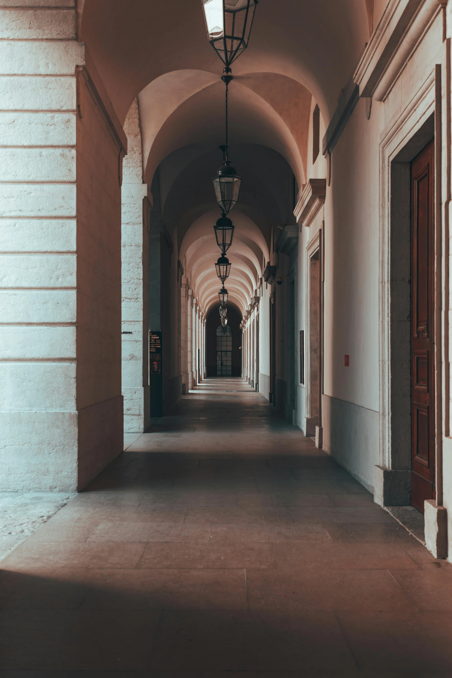 a long hallway with a lamp hanging from the ceiling, pexels contest winner, neoclassicism, dry archways and spires, profile image, shady alleys, university