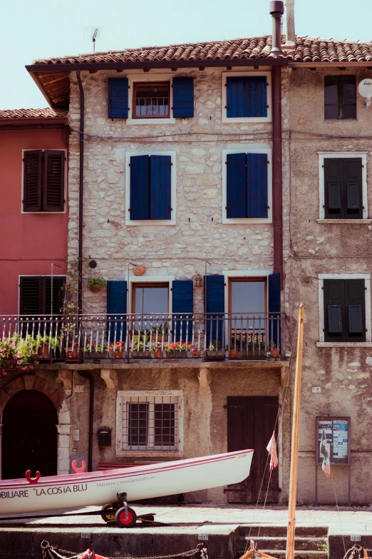 a couple of boats that are sitting in the water, an album cover, inspired by Canaletto, pexels contest winner, in front of a two story house, blue shutters on windows, old color photograph, sienna