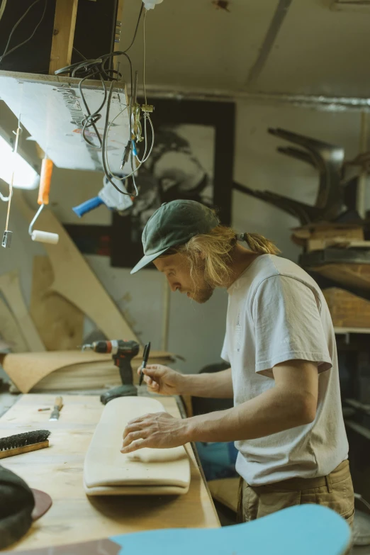 a man sitting at a table working on a piece of wood, a portrait, by Jessie Algie, trending on unsplash, in his basement studio, ocean dept, thumbnail, sydney hanson
