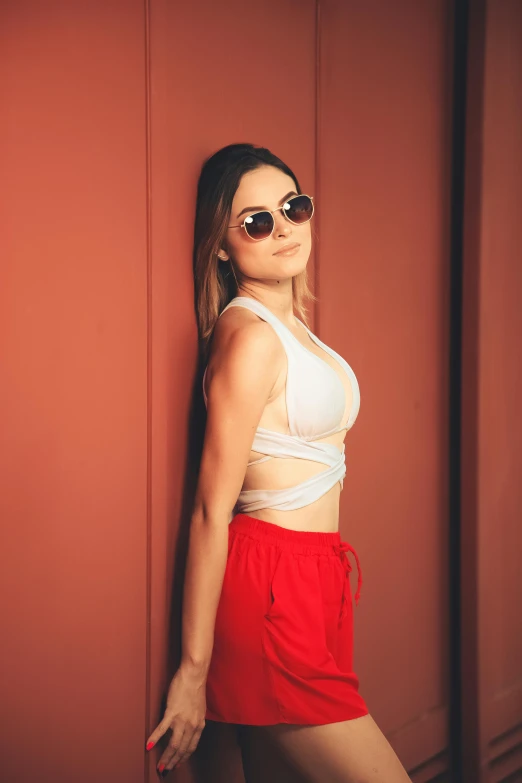 a woman in a white top and red shorts, inspired by Elsa Bleda, trending on pexels, sun glasses, indoor picture, beautiful midriff, frontal pose