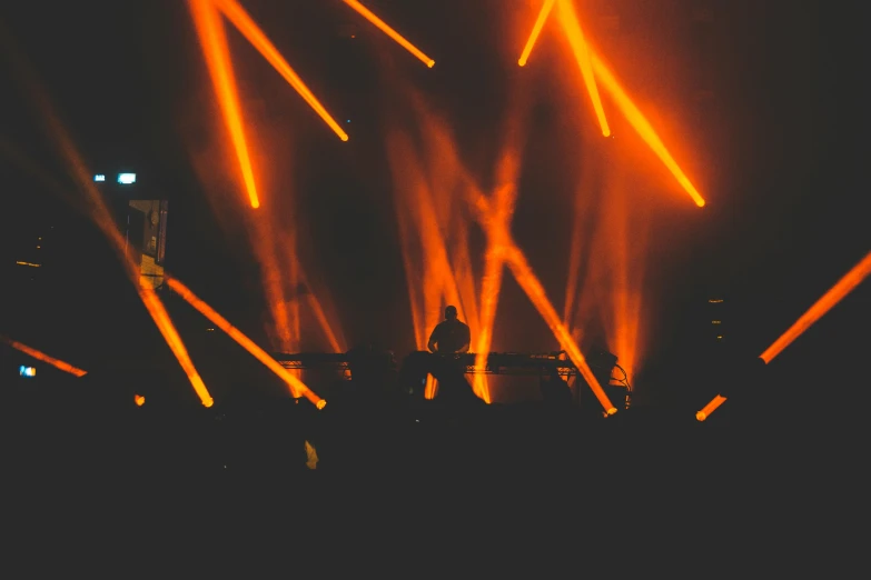 a group of people standing on top of a stage, by Niko Henrichon, unsplash contest winner, light and space, glowing orange lasers, stage at a club, avatar image, flume cover art