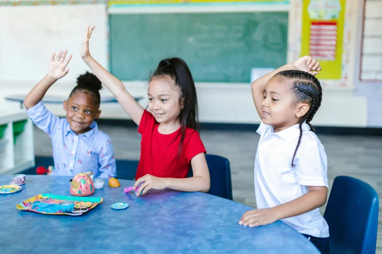 a group of children sitting at a table in a classroom, by Lena Alexander, pexels contest winner, waving, playing games, vannessa ives, essence