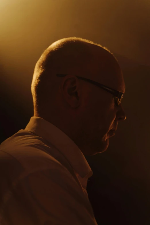 a man wearing glasses and a white shirt, an album cover, inspired by Einar Hakonarson, unsplash, in a movie still cinematic, bald, light lighting side view, still frame from a movie