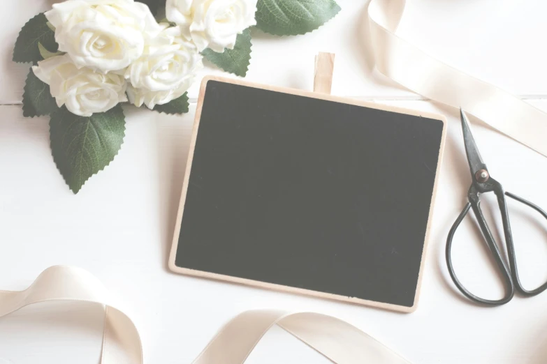 a blackboard surrounded by white flowers and a pair of scissors, cream white background, background image, square pictureframes, wedding