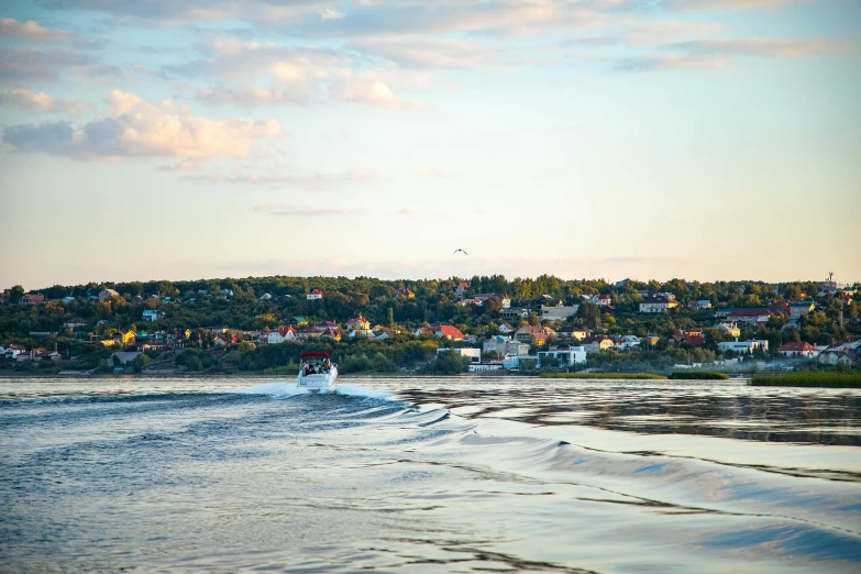 a person riding a surfboard on top of a body of water, a picture, inspired by Wilhelm Marstrand, pexels contest winner, swedish houses, late summer evening, bucklebury ferry, seen from a distance