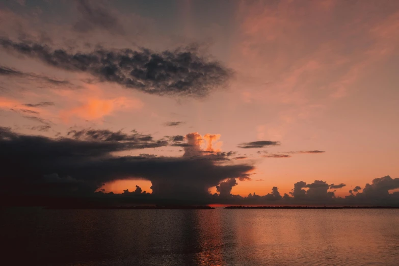 a large body of water under a cloudy sky, a picture, pexels contest winner, romanticism, orange / pink sky, humid evening, unsplash photo contest winner, fan favorite