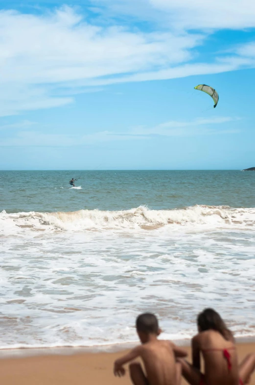 a group of people sitting on top of a sandy beach, a ragdoll cat windsurfing, flying over the ocean, pembrokeshire, square