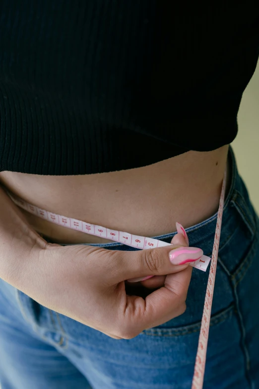 a woman measuring her waist with a tape, by Nicolette Macnamara, trending on pexels, an anthropomorphic stomach, bubblegum body, detail shot, colour photograph