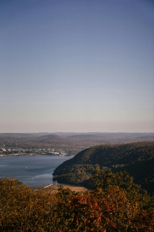 a large body of water surrounded by trees, unsplash, hudson river school, entire city in view, 8 k -, hills, late summer evening