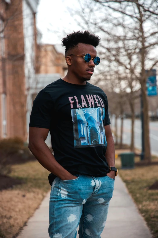 a man standing on a sidewalk with a skateboard, an album cover, inspired by Terrell James, pexels contest winner, black arts movement, black t - shirt, flaming, flawless beauty, dc marvel fashion