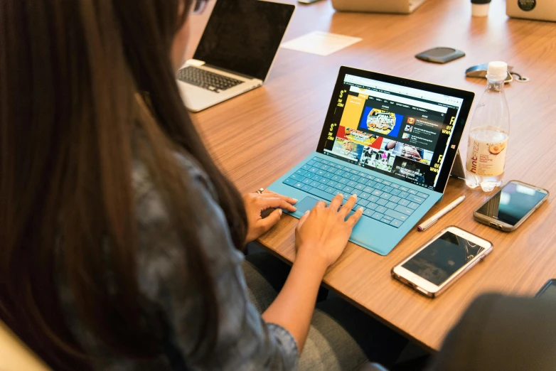 a woman sitting at a table using a laptop computer, pexels contest winner, surface, mobile learning app prototype, color”, square