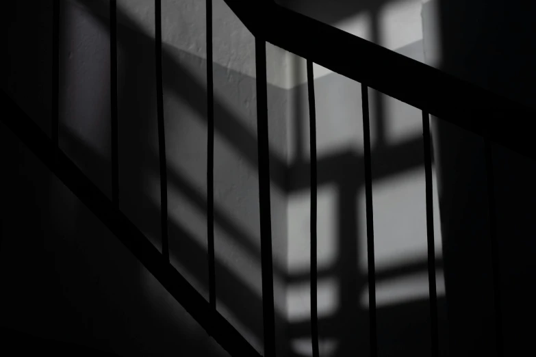 a black and white photo of a staircase, inspired by André Kertész, pexels contest winner, light and space, silhouette :7, deep shadows and colors, natural prison light, medium format. soft light