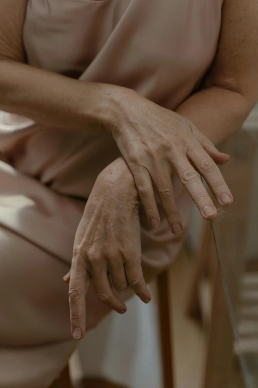 a woman sitting on a chair with a knife in her hand, trending on pexels, hyperrealism, wrinkled muscles skin, holding each other hands, muted browns, blurred