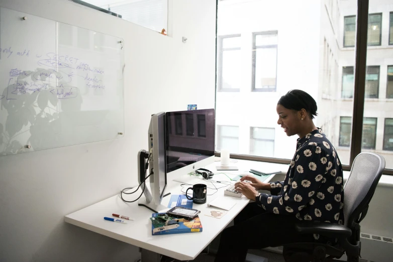 a man sitting at a desk working on a computer, by Jessie Algie, pexels contest winner, black female, cubical meeting room office, profile image, full body image