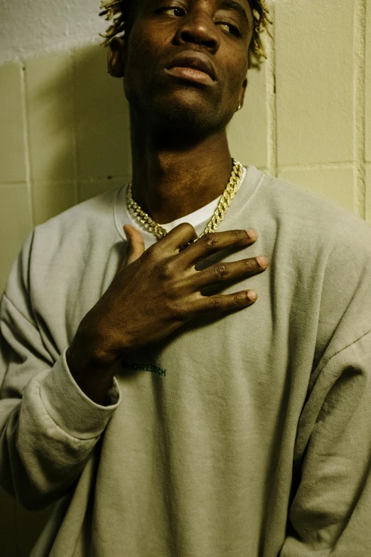 a man that is standing up with his hands on his chest, an album cover, inspired by Terrell James, trending on pexels, gold necklace, yzy gap, profile pic, very very low quality picture