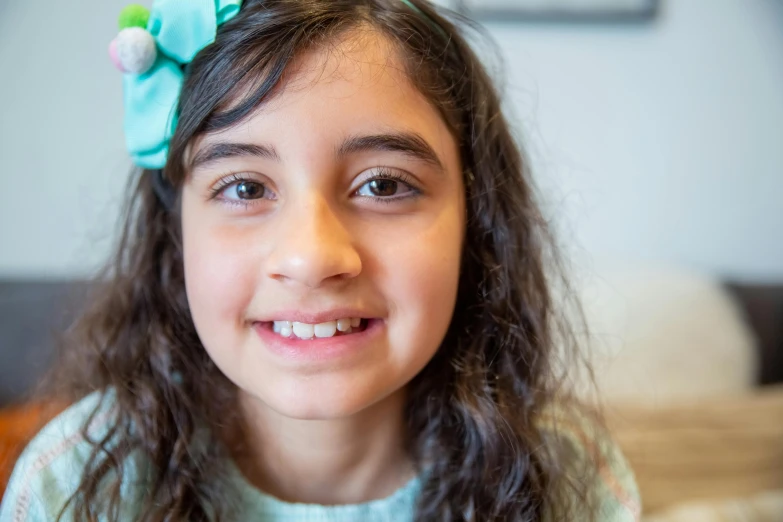 a young girl with a flower in her hair, pexels contest winner, hurufiyya, smiling at the camera, teal headband, avatar image, middle eastern skin