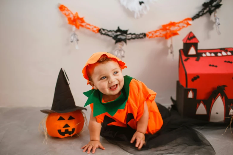 a baby dressed up in a halloween costume, by Julia Pishtar, shutterstock, decoration around the room, while smiling for a photograph, orange and black, instagram post