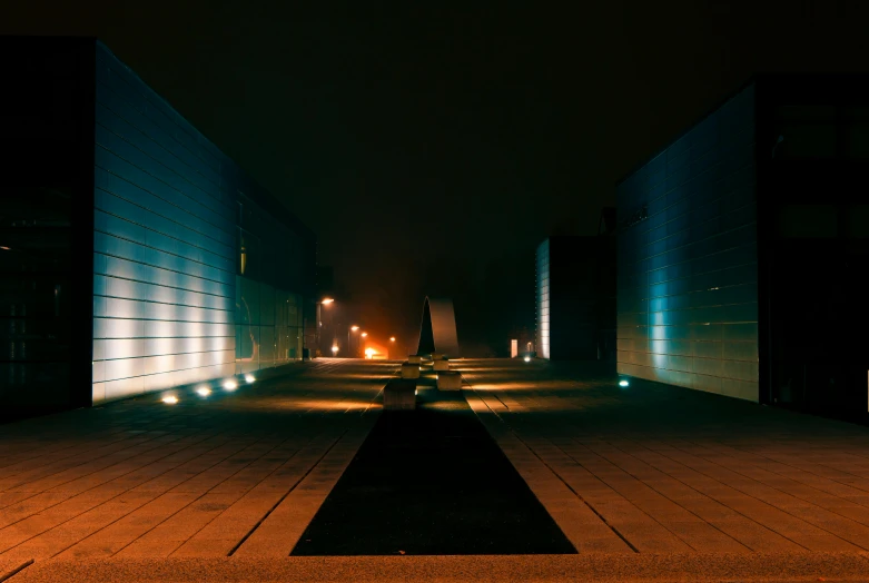 a couple of benches sitting on top of a sidewalk, by Sebastian Spreng, visual art, symmetric lights and fog, military buildings, dark teal lighting, background is a low light museum