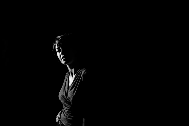 a black and white photo of a woman in the dark, a black and white photo, backlight studio lighting, candid!! dark background, dark negative space, shot with sony alpha