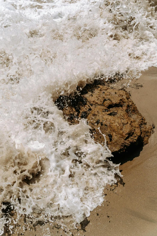 a person riding a surfboard on top of a sandy beach, an album cover, unsplash, renaissance, organic swirling igneous rock, water splashes, brown mud, high angle close up shot