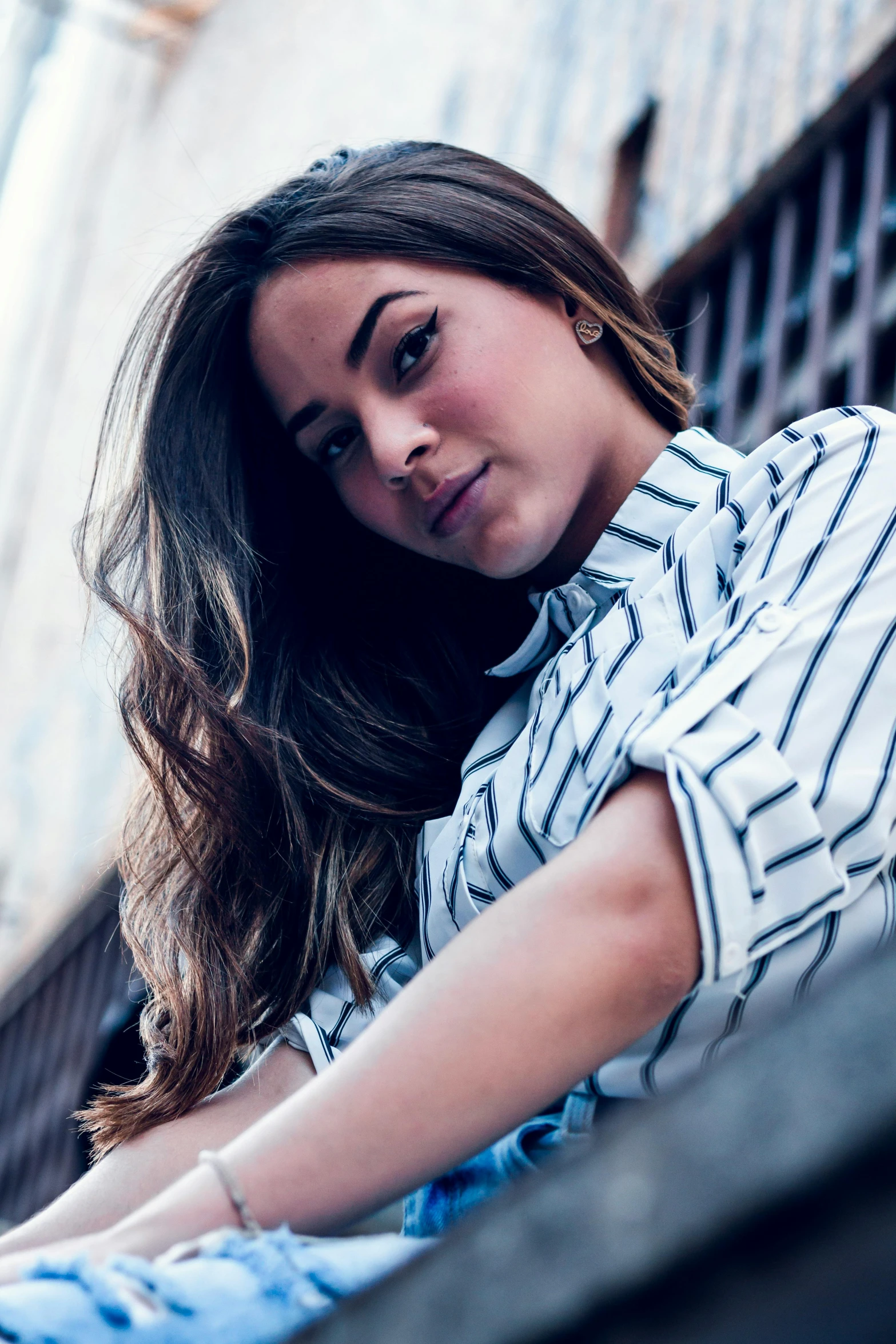 a woman sitting on the steps of a building, a portrait, by Robbie Trevino, unsplash, wearing stripe shirt, chloe bennet, icon, profile image