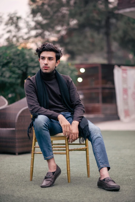 a man sitting on top of a wooden chair, by Ismail Acar, pexels contest winner, wearing turtleneck, wearing a dark shirt and jeans, shabab alizadeh, androgynous person