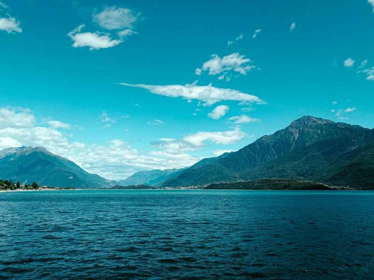 a large body of water with mountains in the background, by Julia Pishtar, pexels contest winner, boka, blue sky, green and blue, high drama