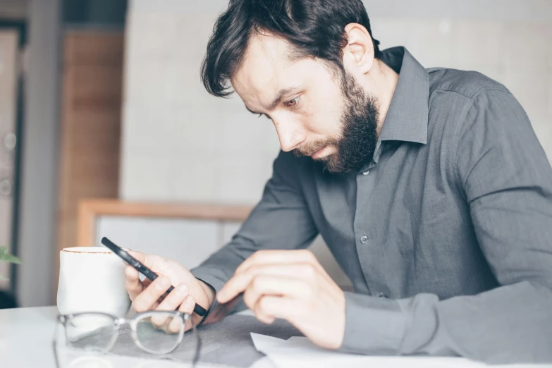 a man sitting at a table using a cell phone, a photo, concentration, sharp focus », grey, thumbnail