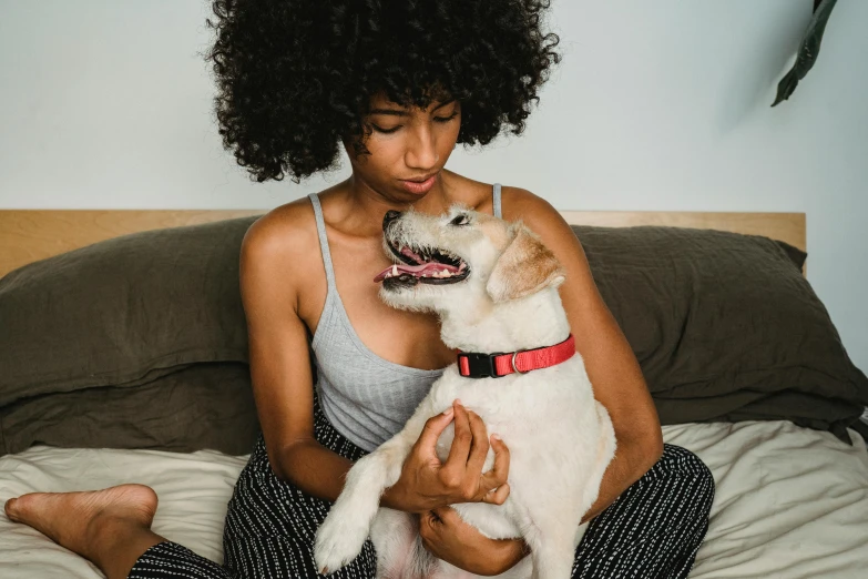 a woman sitting on a bed holding a dog, trending on pexels, renaissance, african american woman, thumbnail, 8, tummy