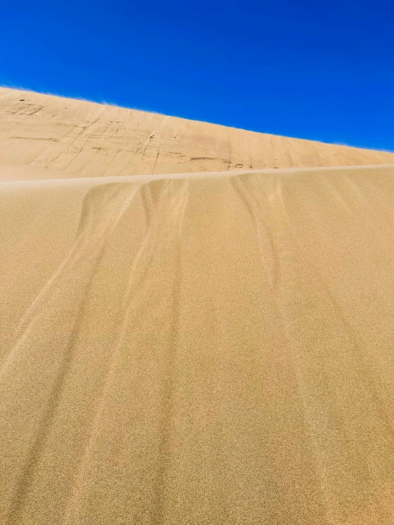 a sand dune with a blue sky in the background, falling sand inside, highly upvoted, profile image