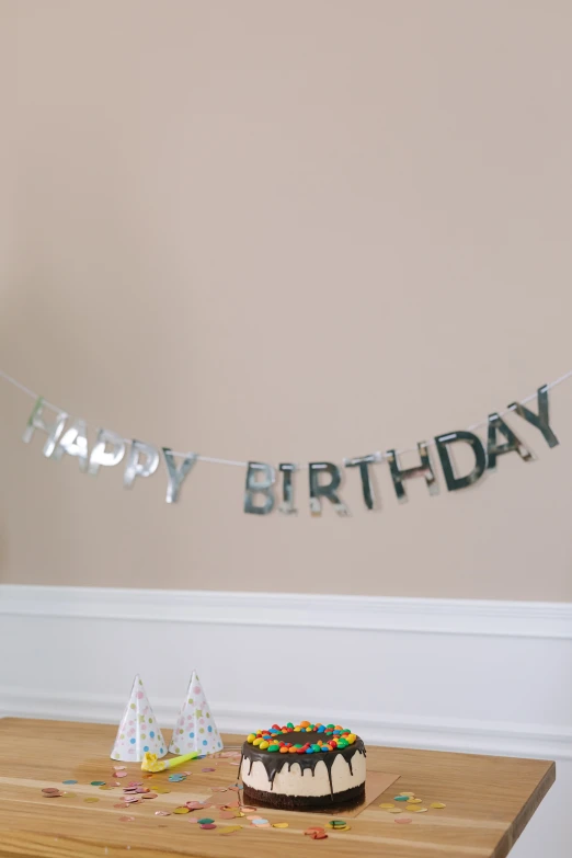 a birthday cake sitting on top of a wooden table, a picture, bubble letters, silver，ivory, full product shot, hanging