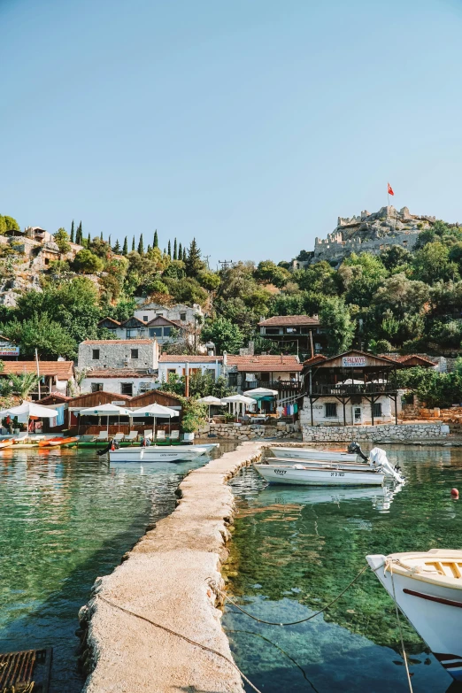 a group of boats sitting on top of a body of water, hurufiyya, cypresses and hills, quaint village, crystal clear blue water, tiled roofs