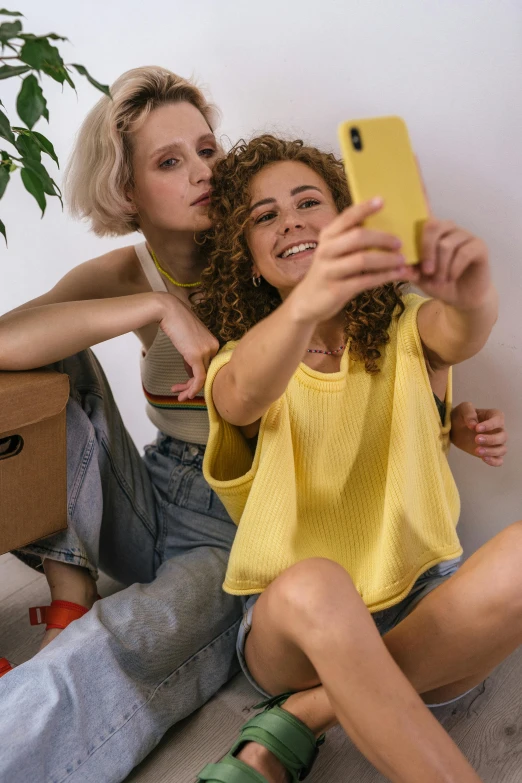 two women sitting on the floor taking a selfie, trending on pexels, renaissance, wearing a modern yellow tshirt, flirting, short curly blonde haired girl, snapchat photo