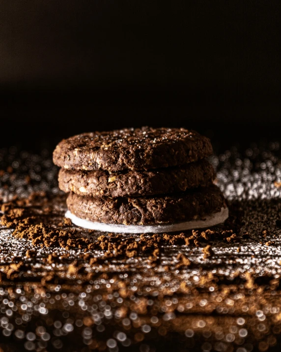 a stack of cookies sitting on top of a table, by Daniel Seghers, dark glitter, fuji choco, profile image, lunar soil