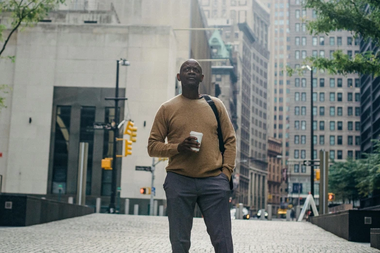 a man standing in the middle of a city street, by Nyuju Stumpy Brown, drinking a cup of coffee, a bald, promotional image, ignant
