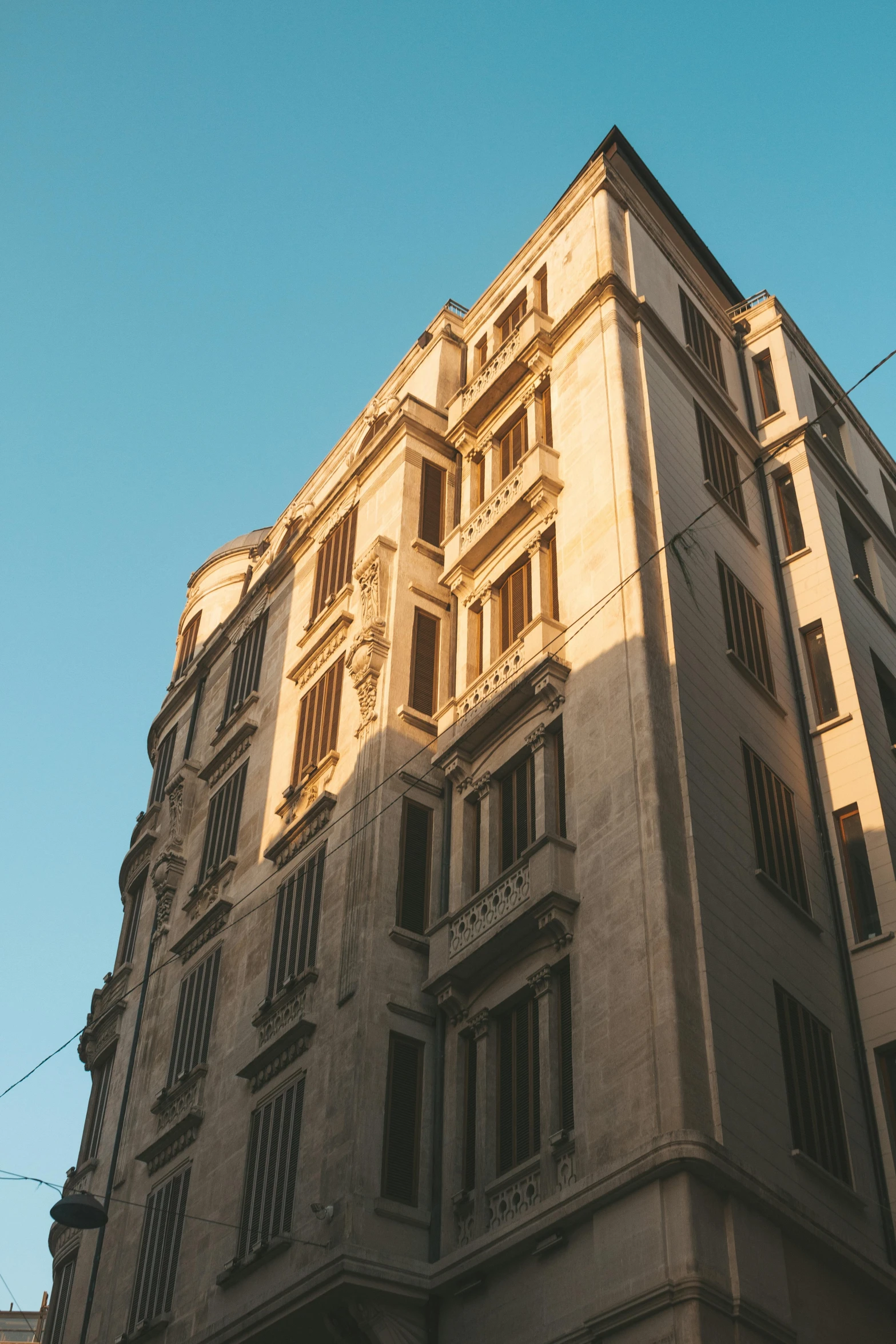 a tall building sitting on the side of a street, inspired by Gianfredo Camesi, neoclassicism, golden hour photograph, rome, exterior, concrete housing